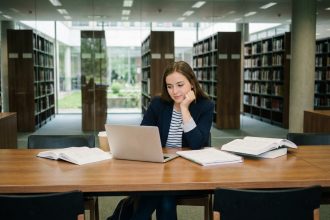Jeune femme concentrée dans une bibliothèque universitaire moderne