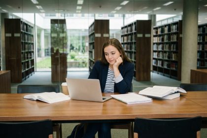 Jeune femme concentrée dans une bibliothèque universitaire moderne
